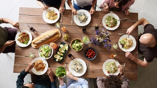 Personas comiendo en una mesa / Foto: Canva