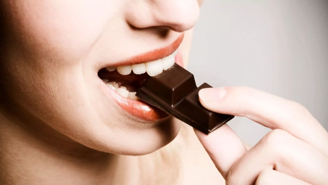 Mujer comiendo un trozo de chocolate / Foto: Canva