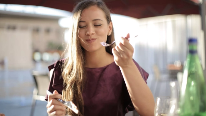 Mujer disfrutando de una comida / Foto: Canva