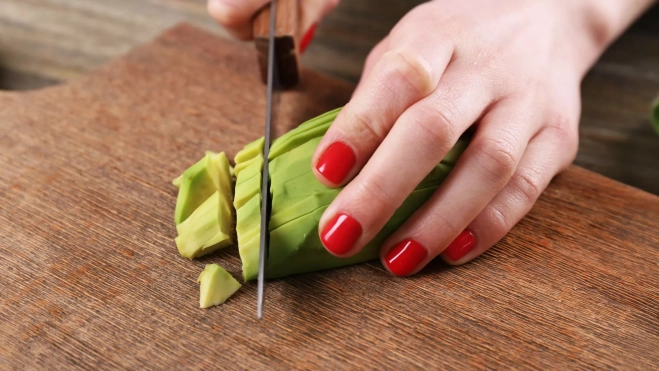 Mujer cortando un aguacate / Foto: Canva