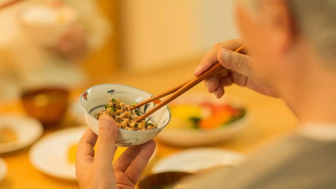 Señor comiendo natto en un cuenco / Canva