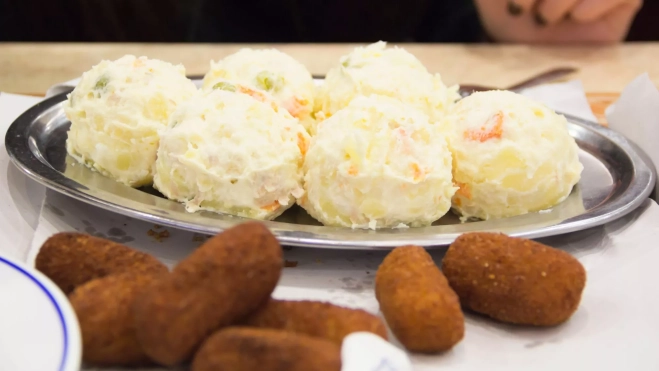 Bolas de ensaladilla rusa y croquetas en un bar / Canva