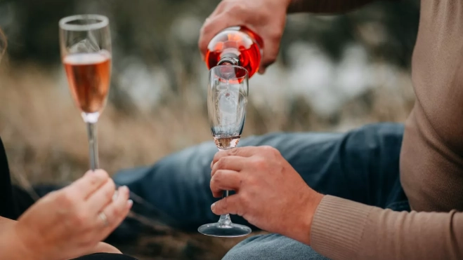 Una pareja comparte una botella de vino rosado PEXELS