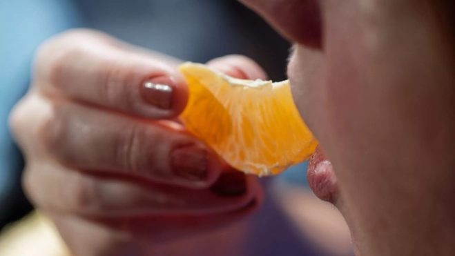 Mujer comiendo mandarina / Canva